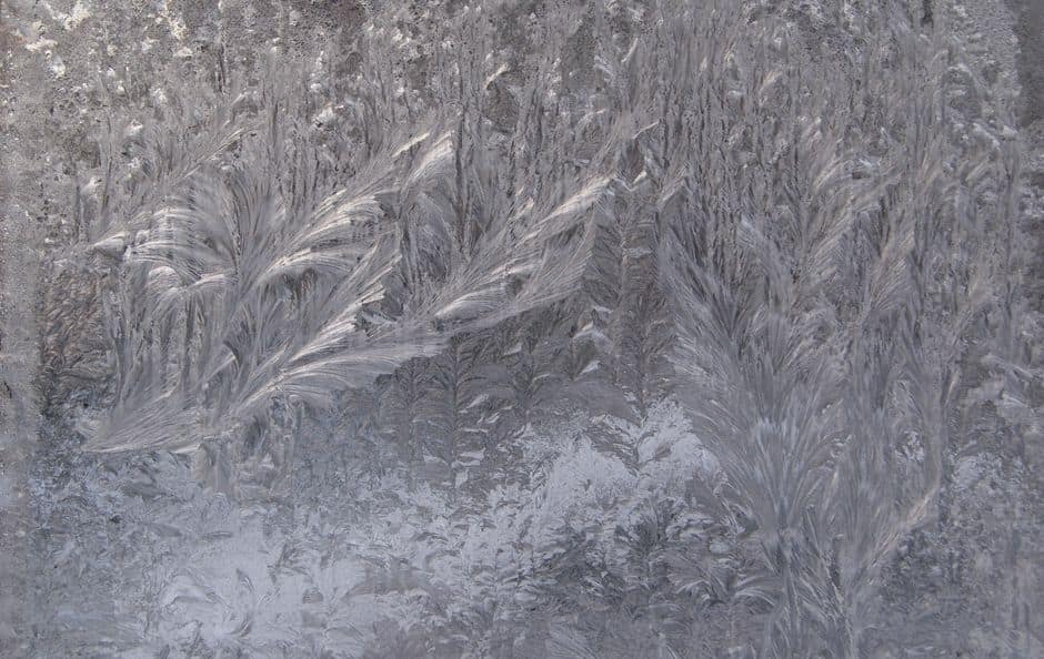 Intricate frost patterns forming unique designs on a window during winter.