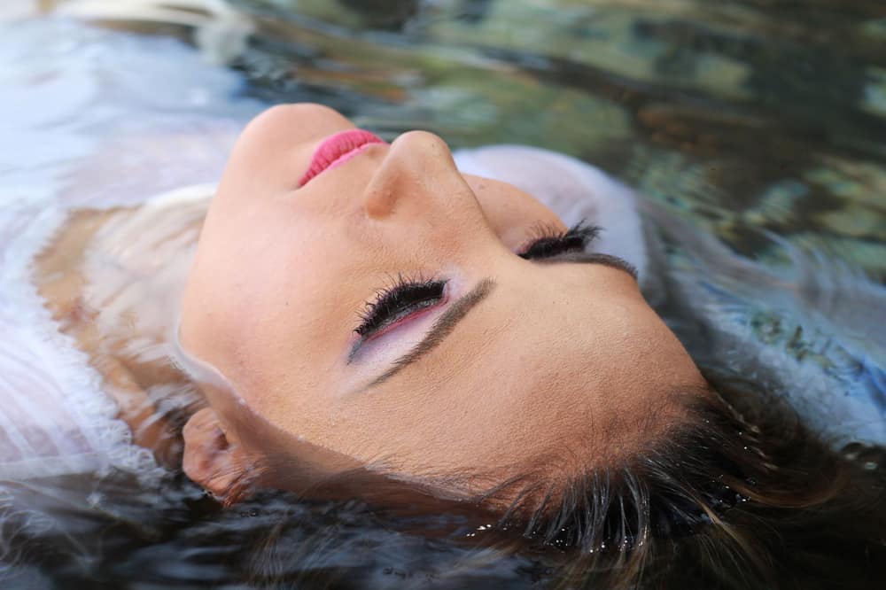 A serene close-up of a woman's face floating in tranquil water, showcasing tranquility and beauty.